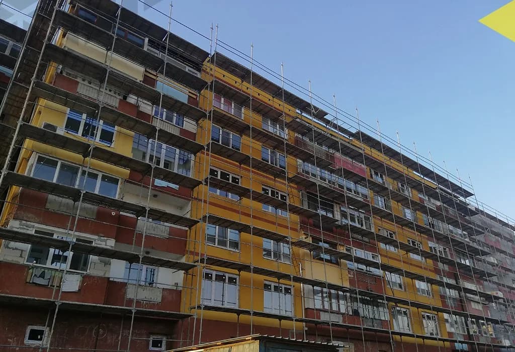 Фасадно скеле по жълто-червена жилищна сграда, погледната отдолу